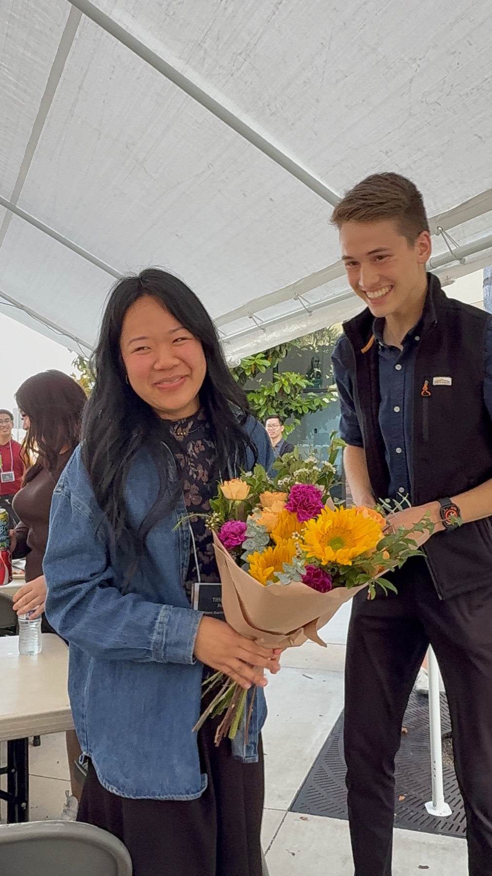 Tiffany and Josiah smiling together with a bouquet of flowers