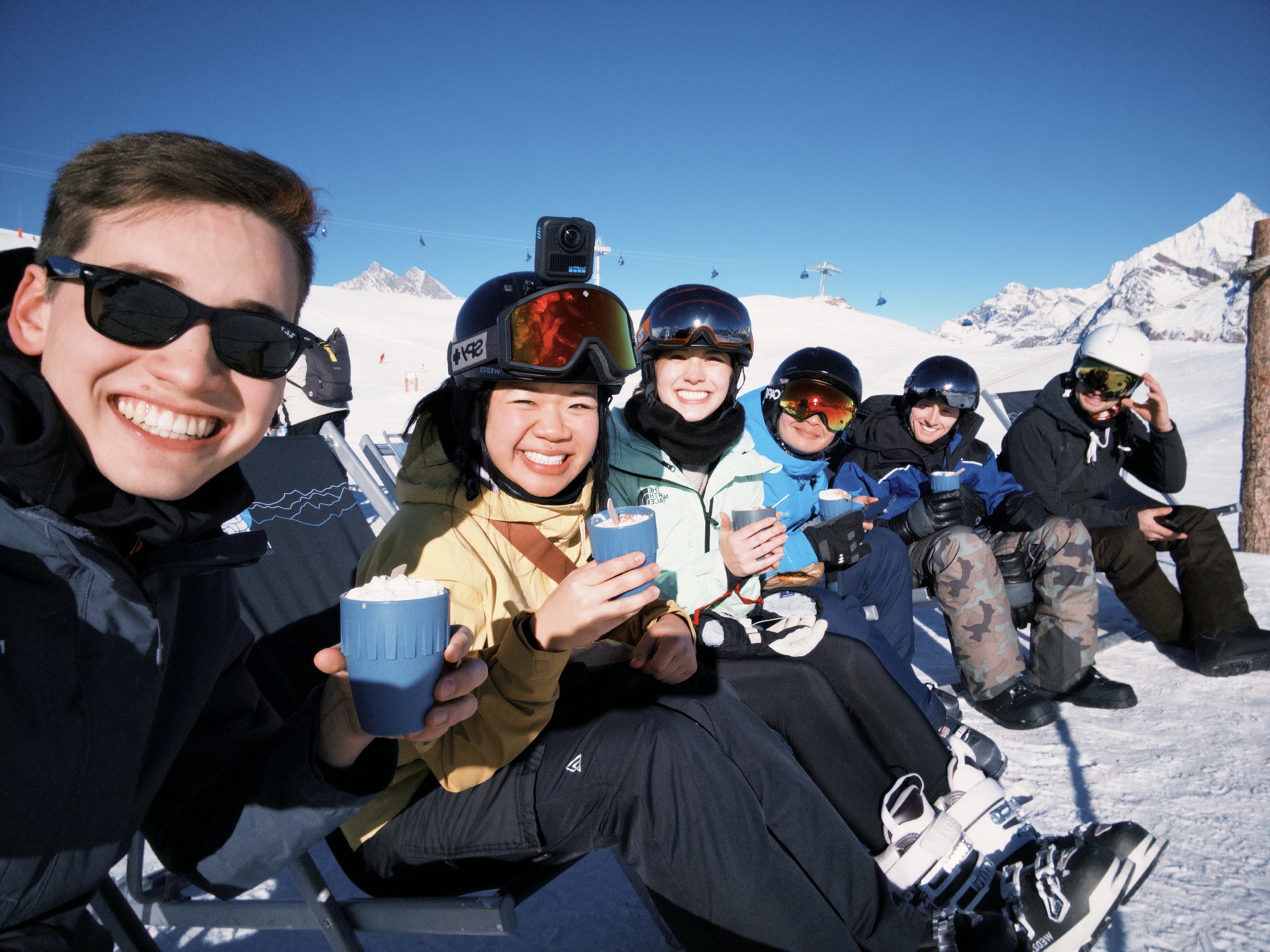 Friends enjoying hot drinks together on a sunny ski slope