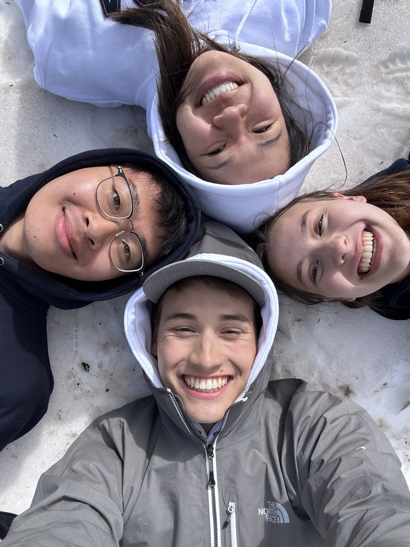 Four friends lying in a circle and smiling up at the camera